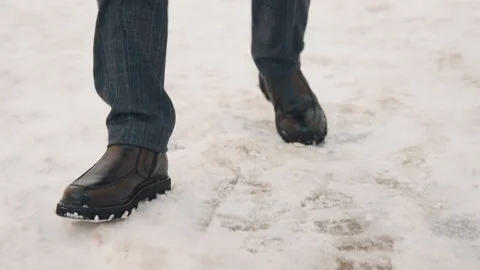 Close up man black leather shoes walking fresh snow ground visible footsteps Stock Footage 344865653