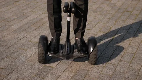 Close-up of a man in a black suit riding around the park on a gyro scooter. Stock Footage 222992745