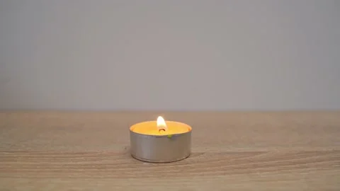 A close-up of a man blows out the flame of a yellow scented candle on a table Stock Footage 203211992