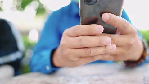 Close up of a man in a blue shirt using a smartphone 스톡 동영상 147956861