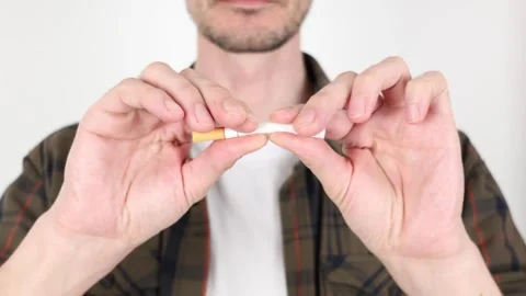 Close-up of a man, breaking a cigarette in front of himself with his hands 動画素材 307416948