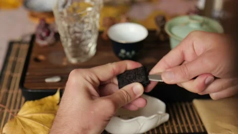 Close-up. a man breaks Chinese pressed puer tea or da hong pao with a knife.  Stock Footage 220536963