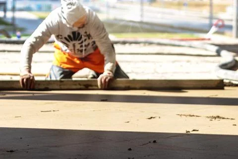 Close up of man builder placing screed rail on the floor covered with sand-ce Stock Photos