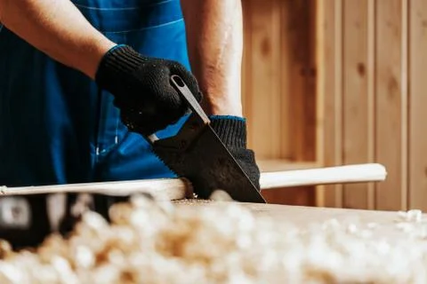 Close up  of the a man builder saws a board with a  saw in the workshop. Cons Stock Photos