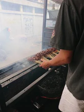 Close up man burning chicken satay or sate Stock Photos
