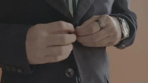 Close-up of a man buttoning a black blazer over a striped shirt. 스톡 동영상 330155877