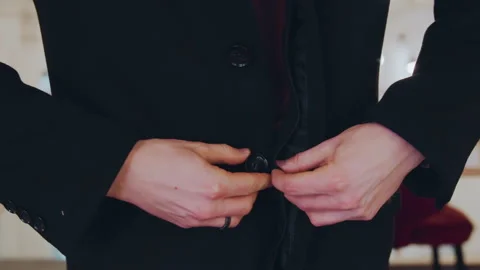Close up of man buttoning front closure on his black coat with closeup hands Stock Footage 344876990