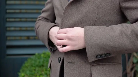 Close-up of a man buttoning his coat. Young elegant male businessman in brown 動画素材 144494483