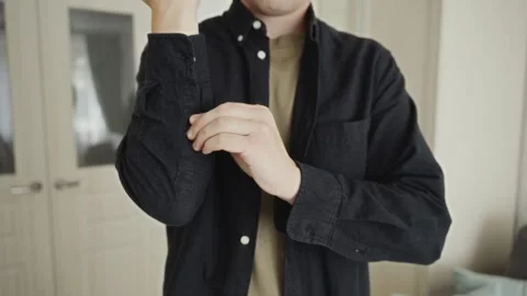 Close-up of man buttoning shirt as part of daily self-care Stock Footage 316580547