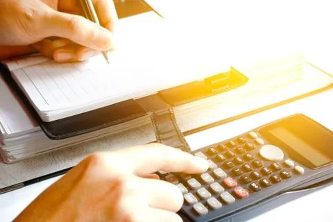 Close up of man with calculator counting making notes at home, hand is writ.. Stock Photos