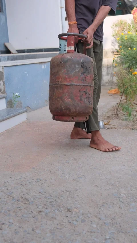 Close up of a man carrying an empty rusty LPG gas cylinder Stock Footage 333057947