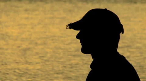 Close up of a man casting his rod and reel at sunset. Silhouetted fly fishing Stock Footage 33833481