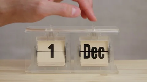 Close-up on a man changing dates Dec 31 to Jan 1 on calendar with studio light Video stock 77409465