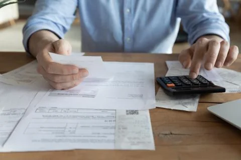 Close up man checking bills, holding receipt, using calculator Stock Photos