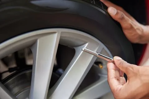 Close-Up Of Man Checking Car Tyre Pressure With Gauge 写真素材