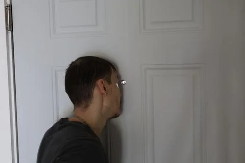 Close up man checking door peephole side view security concept 写真素材