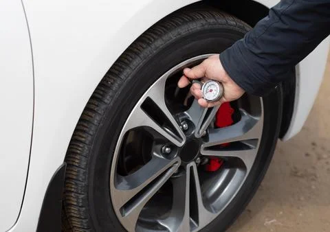 Close-up of a man checking tire pressure on a modern car with an analog tire pre Foto stock