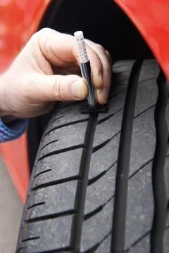 Close-Up Of Man Checking Tread On Car Tyre With Gauge Stock Photos