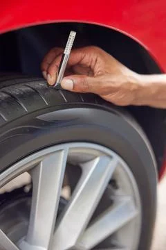 Close-Up Of Man Checking Tread On Car Tyre With Gauge Stock Photos