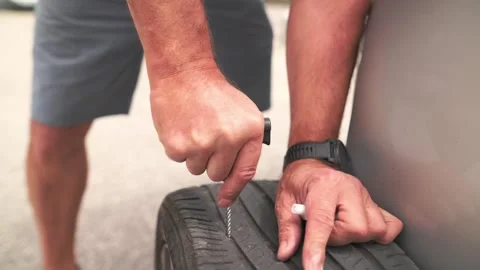 Close-up of man checking worn tire tread with tool during roadside maintenance Vidéo 318355811