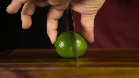 Close-Up Man Chef Cuts Fresh Fruits Lemon And Lime On Wooden Cutting Board Stock Footage 104983250