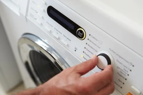 Close Up Of Man Choosing Cycle Program On Washing Machine Foto stock