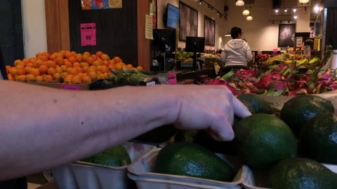 Close-up of a man choosing a fresh avocado in a grocery vegetable store Stock Footage 275888980