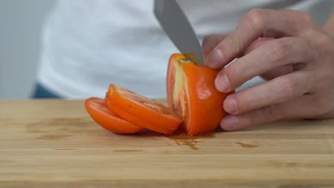 Close up of a man chopping tomato vegetables on chopping board in a kitchen Stock Footage 113629003