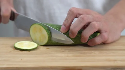 Close up of a man chopping zucchini vegetable on chopping board in a kitchen Stock Footage 113515375