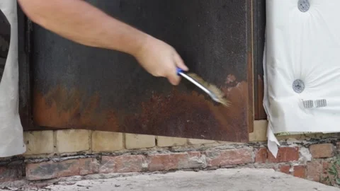 Close-up of a man cleaning heavy rust from a steel exterior door with a wir.. Video stock 347011339