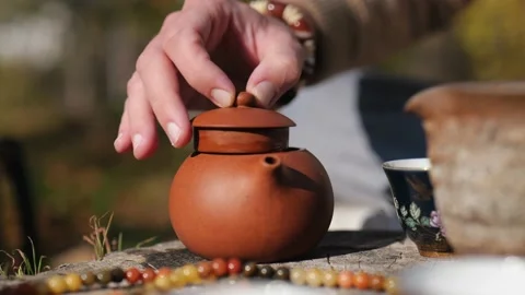 Close-up. a man closes the lid of clay tea and pours tea into a bowl. chine.. Stock Footage 229858837