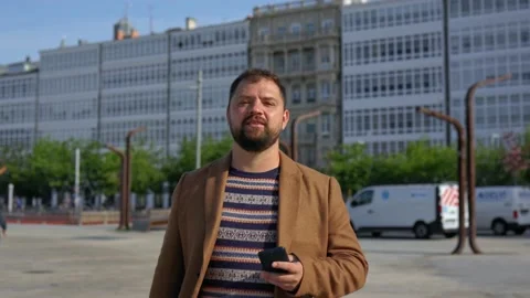 A close-up of a man in a coat walks down the street to the camera, smiling and Stock Footage 221804114