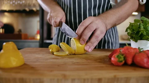 Close-up Man Cook Cuts Fresh Fruits Lemon and Strawberry on Wooden Cutting Board Stock Footage 142802322
