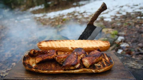 Close up of man cooking sandwich with meat near campfire in early spring forest Stock Footage 309028956