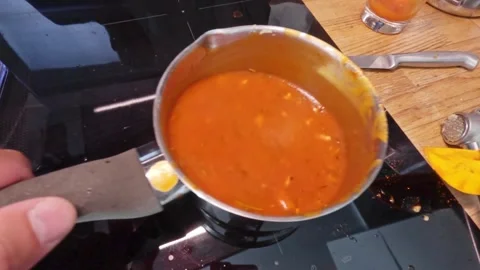 Close-up of a man cooking tomato sauce in a pot on an induction stove, addi.. Video stock 284873630