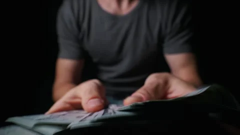 Close Up of Man Counting Stack of Us Hundred Dollar Bills in Dark Room Stock Footage 339366402