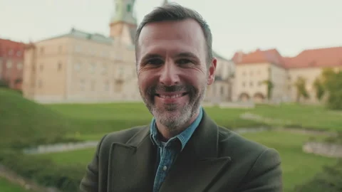 Close up, man crosses his arms, looks at the camera and smiles at the old city Video stock 227134833