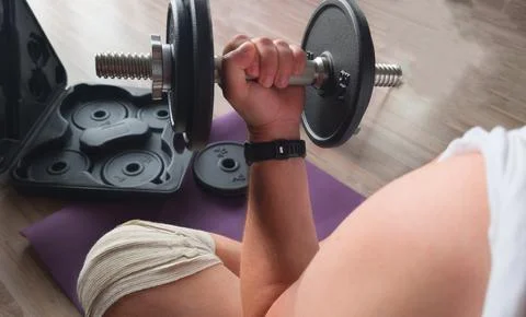 Close-up of a man curling an adjustable black dumbbell during a home workout  Stock Photos