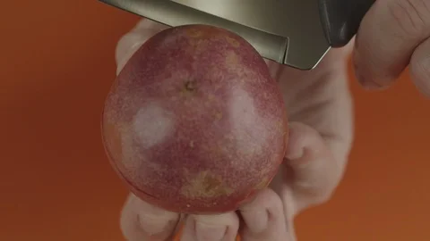 Close-up man cuts fresh passion fruit in half with steel knife Stock Footage 125066624