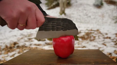 Close up of man cutting fresh red peppers on wooden board near campfire Stock Footage 308719569