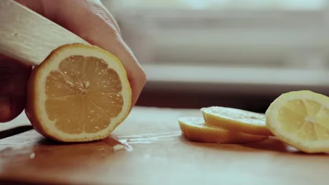 Close up of a man cutting the lemon on a cutting board in kitchen. Lemon juice c Stock Footage 302362436
