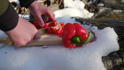 Close up of man cutting red peppers on board on background river at winter time Stock Footage 301363836