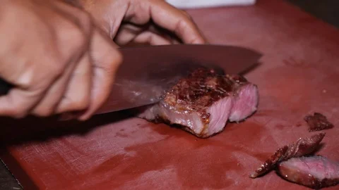 Close up of man cutting steak on red board in kitchen, Kuala Lumpur, Malaysia Stock Footage 146544282