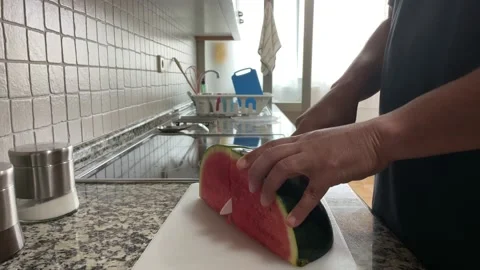 Close up of man cutting a watermelon with a ceramic knife in his home kitchen Stock Footage 160476571