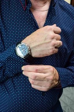 Close up of man in dark blue dotted shirt fixing his sleeve cuff Фото