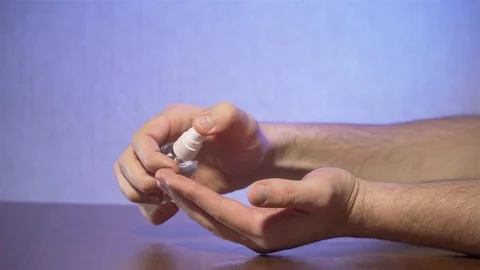 Close up of man dispensing liquid spray sanitizer into his hands and cleaning Stock Footage 127652042