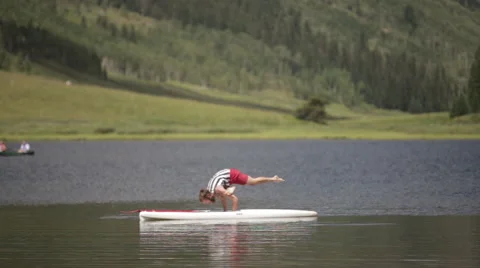 Close up man does yoga on paddle board in mountain lake Stock Footage 56565697