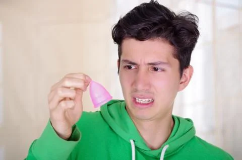Close up of a man doing an disgusting face while is holding a menstrual cup in Stock-Fotos
