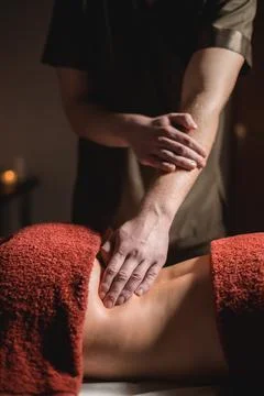 Close-up of a man doing a lower back massage to a woman client in a dark room of Stock Photos