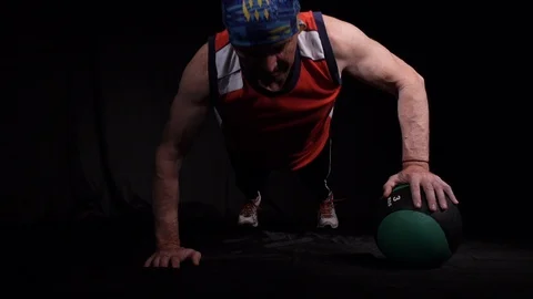 Close up of Man doing Push-ups using one medball, alternately rolling it from Stock Footage 125006731